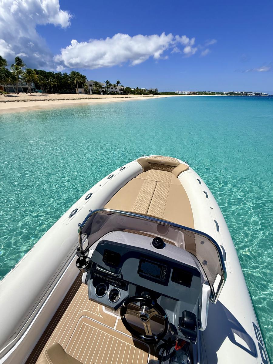 At anchor off Meads Bay, Anguilla: the helm and bow of the RIB, the long white-sand beach and its palm trees